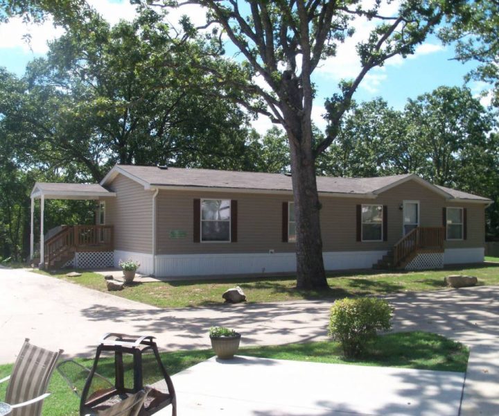 ozark house exterior with lawn and tree at Great Escapes RV Resorts Branson