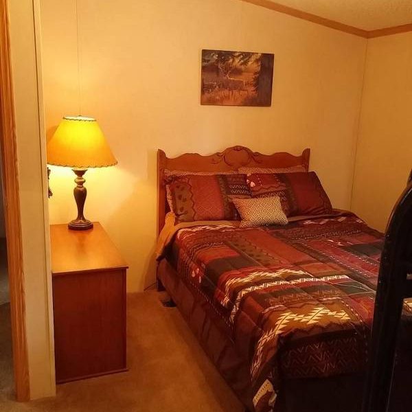 ozark house bedroom with bed and lighting at Great Escapes RV Resorts Branson