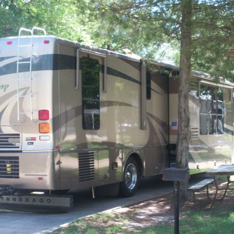 parked rv next to trees and picnic table